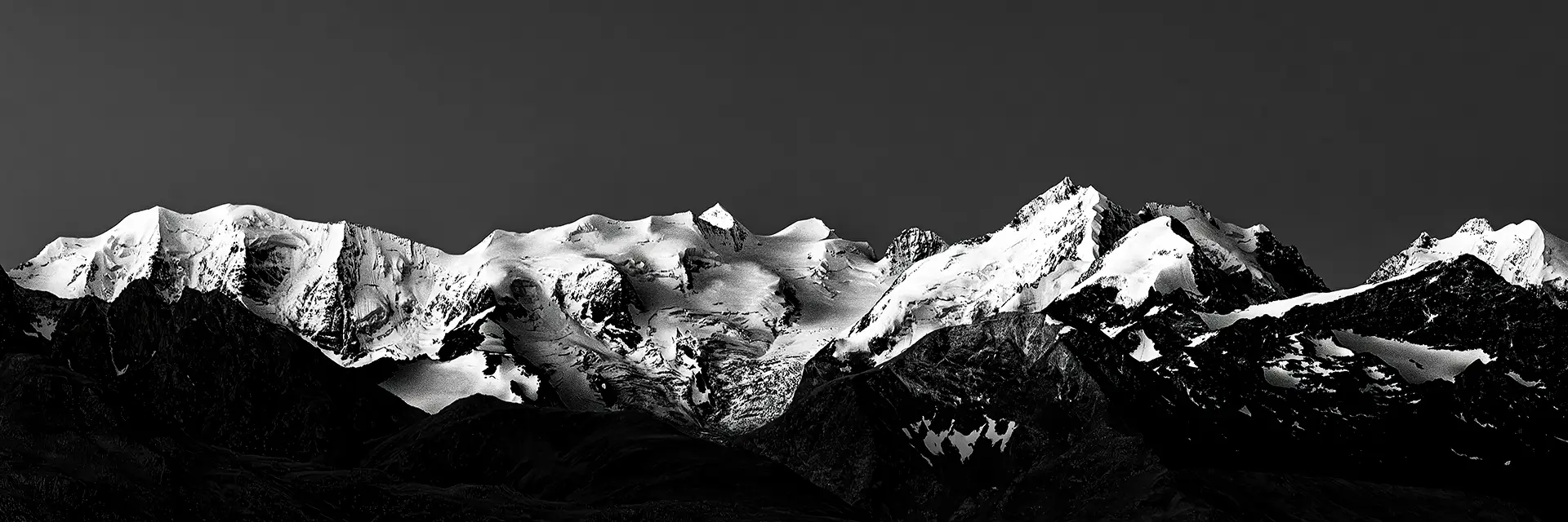 ramatisches Schwarzweiß-Panorama der schneebedeckten Berninagruppe in den Schweizer Alpen – Teaser für die Engadin-Kollektion von Hemmi.photo.
