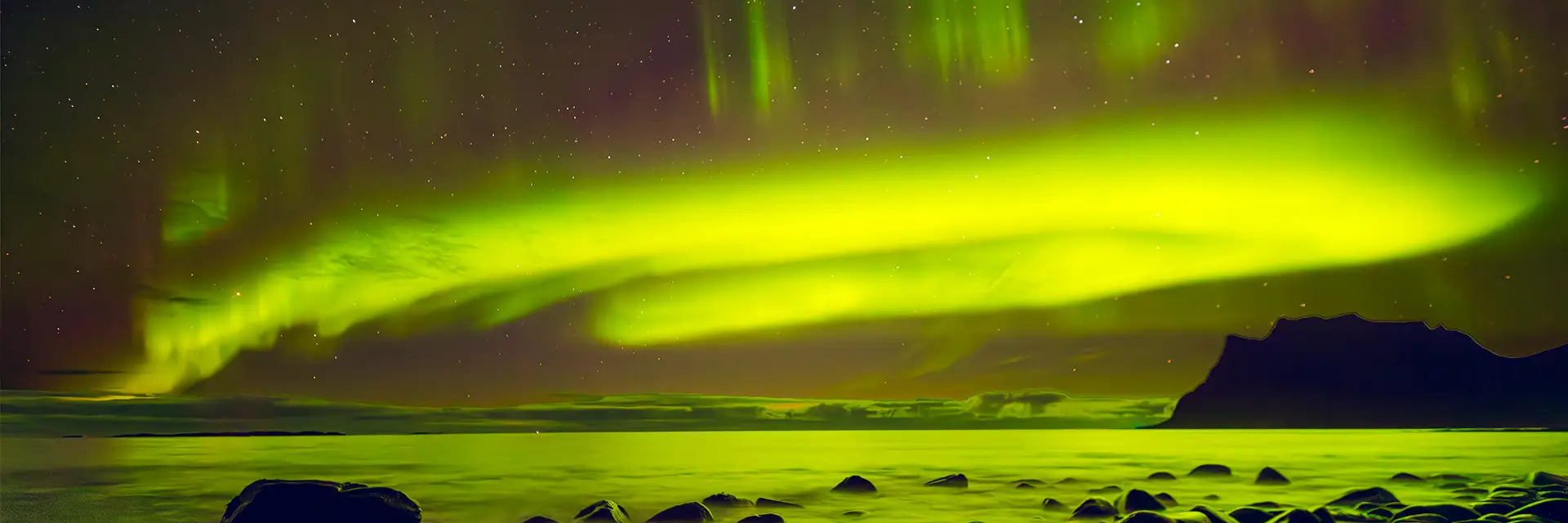 Spektakuläres Panorama-Startbild von leuchtend grünen Nordlichtern (Aurora Borealis) über einem dunklen Fjord an der norwegischen Küste (Lofoten) für Hemmi.photo.